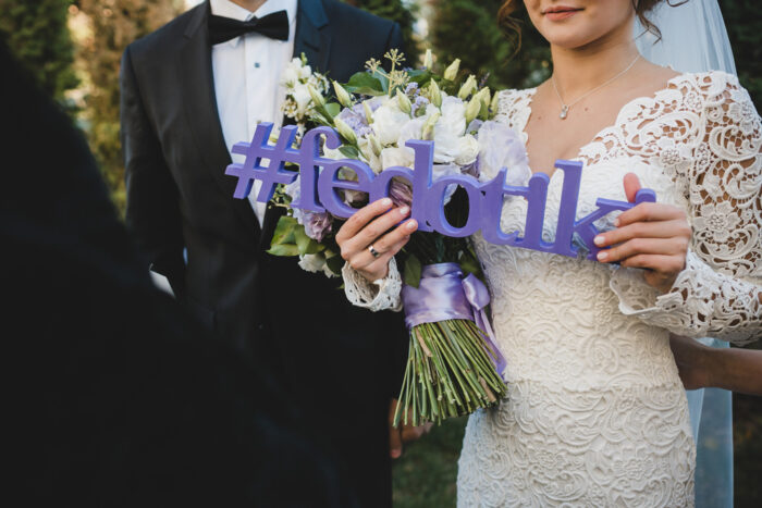 couple holding a wedding hashtag sign