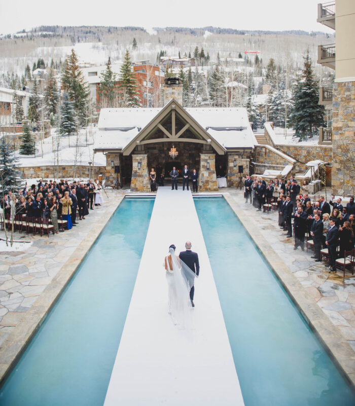 couple walking down the aisle in the middle of a pool in winter